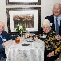 Three people posing in front of table
